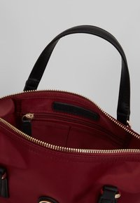 Borsa a tracolla rossa in nylon con dettagli in pelle nera,con cerniera dorata, tasche interne e doppi manici.