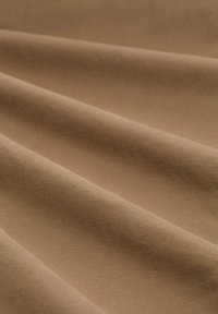 Beige stof met een gladde textuur, die gevouwen lagen toont. Kenmerkt zich door een fijn, subtiel patroon over het oppervlak.