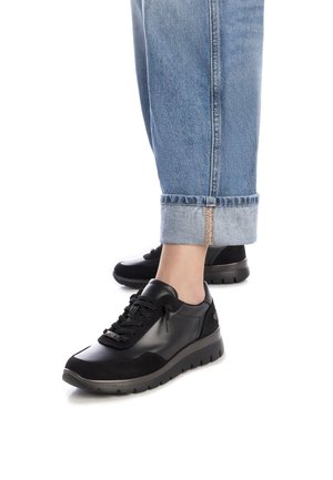 Zapatilla negra hecha de cuero y ante, con puntera redondeada, parte frontal con cordones y acentos texturizados. Diseñada con una suela gruesa y acolchada.