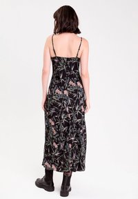 Sort blomster maxi kjole med tynde stropper, der har et botanisk print i pink og grøn. Strømmende stof med en afslappet pasform og ankel længde.
