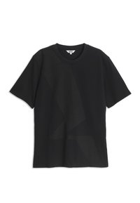 T-shirt noir à manches courtes avec motif géométrique tonal subtil et étiquette de marque Aigle à l'intérieur du col.