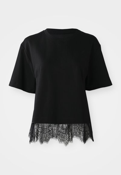 Czarny t-shirt z krótkimi rękawami, zdobiony koronkowym wykończeniem na dole. Koronka ma skomplikowany wzór z falistymi krawędziami i motywami kwiatowymi.