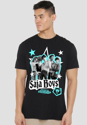 Man wearing black t-shirt featuring five animated male characters framed by stars and text "Saja Boys" and "Kpop Demon Hunters."