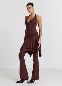Braunes Neckholder-Top mit drapiertem Ausschnitt, kombiniert mit ausgestellten Hosen in passender Farbe, aus glattem, elastischem Stoff. Stilettos vervollständigen den Look.