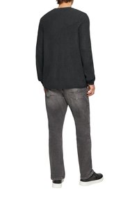 Dunkelgrauer Strickpullover mit strukturierter Oberfläche, Rundhalsausschnitt und langen Ärmeln, kombiniert mit ausgeblichenen grauen Jeans und schwarzen Sneakern.