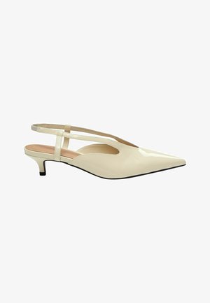 Zapatos de tacón slingback de charol beige con punta puntiaguda, tacón bajo tipo kitten y dos correas entrecruzadas sobre el pie.