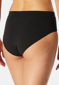 Schwarze Baumwollslips mit hohem Bund, glatter Textur und elastischem Bund. Das Design zeichnet sich durch minimale Nähte und einen klassischen Schnitt aus.