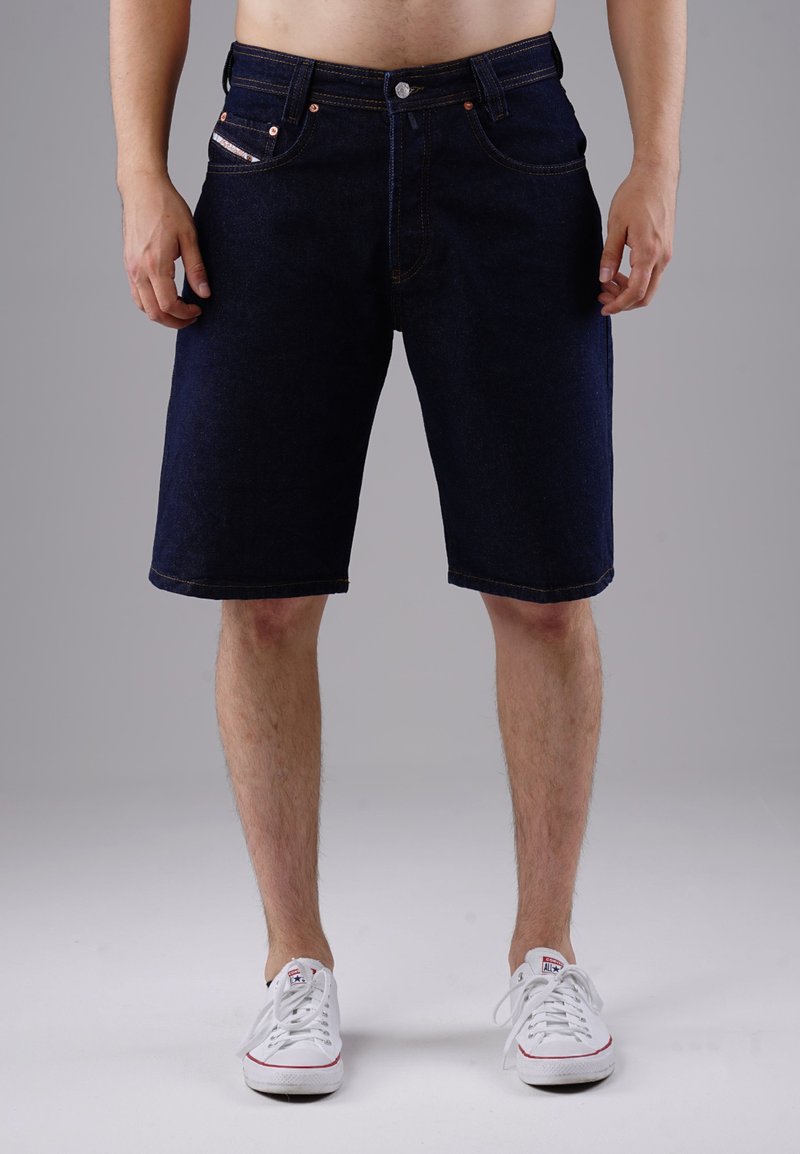 Dark blue denim shorts with five pockets, metal button closure, and contrasting stitching. Hemline is straight and sits just above the knee.