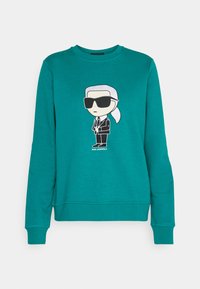 Sudadera turquesa con mangas largas y escote redondo, con una impresión de un personaje con gafas de sol y traje en la parte frontal.