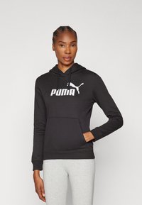Čierna mikina s kapucňou vyrobená z kombinácie bavlny, s prednou kapsou, sťahovacou kapucňou a s bielym logom Puma výrazne zobrazeným na prednej strane.