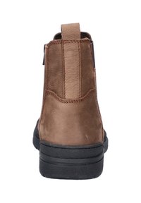 Botte en cuir marron avec semelle en caoutchouc noire, tirant à l'arrière et couture visible, montrée de dos sur un fond blanc.