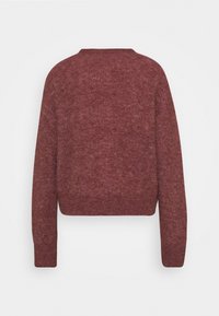 Sweter w kolorze rdzy, krótki, z teksturowanym wykończeniem dzianiny, o luźnym kroju i długich rękawach. Posiada prosty okrągły dekolt i brak widocznych zapięć.