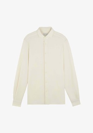 Creme farvet langærmet skjorte med knaplukning og krave-design, blød tekstur og diskret branding på venstre bryst. Ensfarvet uden mønstre.