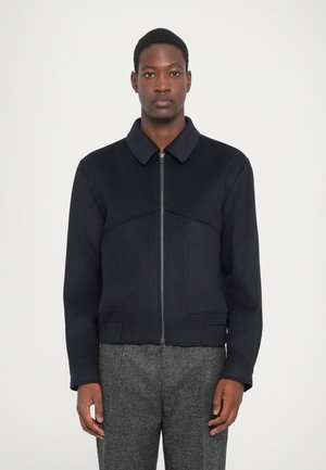 Navy jacket with a collared neck, front zip closure, and textured fabric. Features a fitted design with side pockets and a cropped cut.