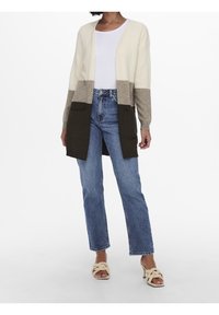 Neulemallinen neuletakki väriltään kerma, beige ja oliivinvihreä. Edestä avoin, pitkät hihat, kaksi etutaskua. Yhdistetty vaaleansinisiin korkeavyötäröisiin farkkuihin.