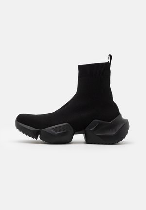 Black high-top sock sneaker with chunky segmented sole and ribbed knit upper extending above the ankle.