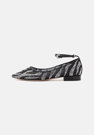 Schwarzer flacher Schuh mit spitzer Zehenpartie, verziert mit silbernen Strasssteinen in einem gewellten Muster und einem schmalen Knöchelriemen. Strukturierter Stoff.