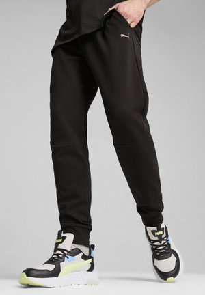 Pantalones deportivos negros con bolsillos laterales y pierna ajustada. Combinados con zapatillas multicolores que cuentan con superposiciones de malla y cuero.