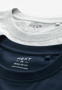 Két rétegben viselt póló, az egyik szürke, a másik tengerészkék. Mindkettő kerek nyakkivágással rendelkezik, és a címke szerint "NEXT M REGULAR FIT, MADE IN BANGLADESH." Textúrált anyag.