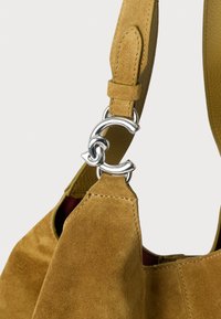 Suède handtas in mosterdgeel met een zilverkleurige schakelketting als accent aan het handvat. Voorzien van een glad lederen interieur en gestikte naden.