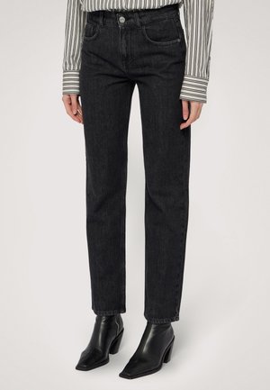 Jeans en denim noir taille haute avec une jambe droite, dotés de poches avant, de passants de ceinture et de détails de couture subtils. Associés à des bottines noires.