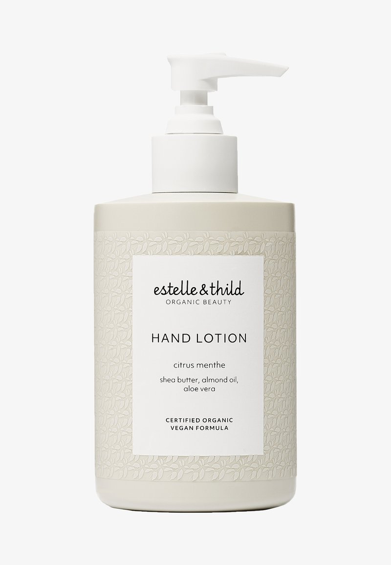 Crema de manos en un recipiente beige con bomba. El diseño texturizado presenta un patrón de hojas. La etiqueta indica un aroma a menta cítrica y fórmula vegana.