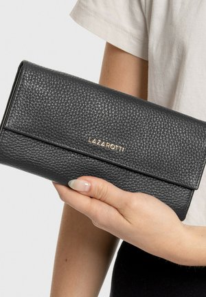 Black textured leather wallet with a flap closure, featuring gold-colored branding. Handheld with a neutral background.