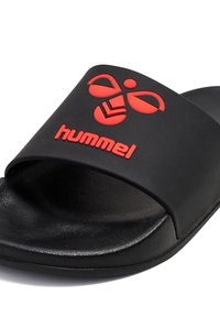 Sandale noire à enfiler avec logo hummel rouge et motif abeille sur la sangle, semelle intérieure texturée et semelle lisse.
