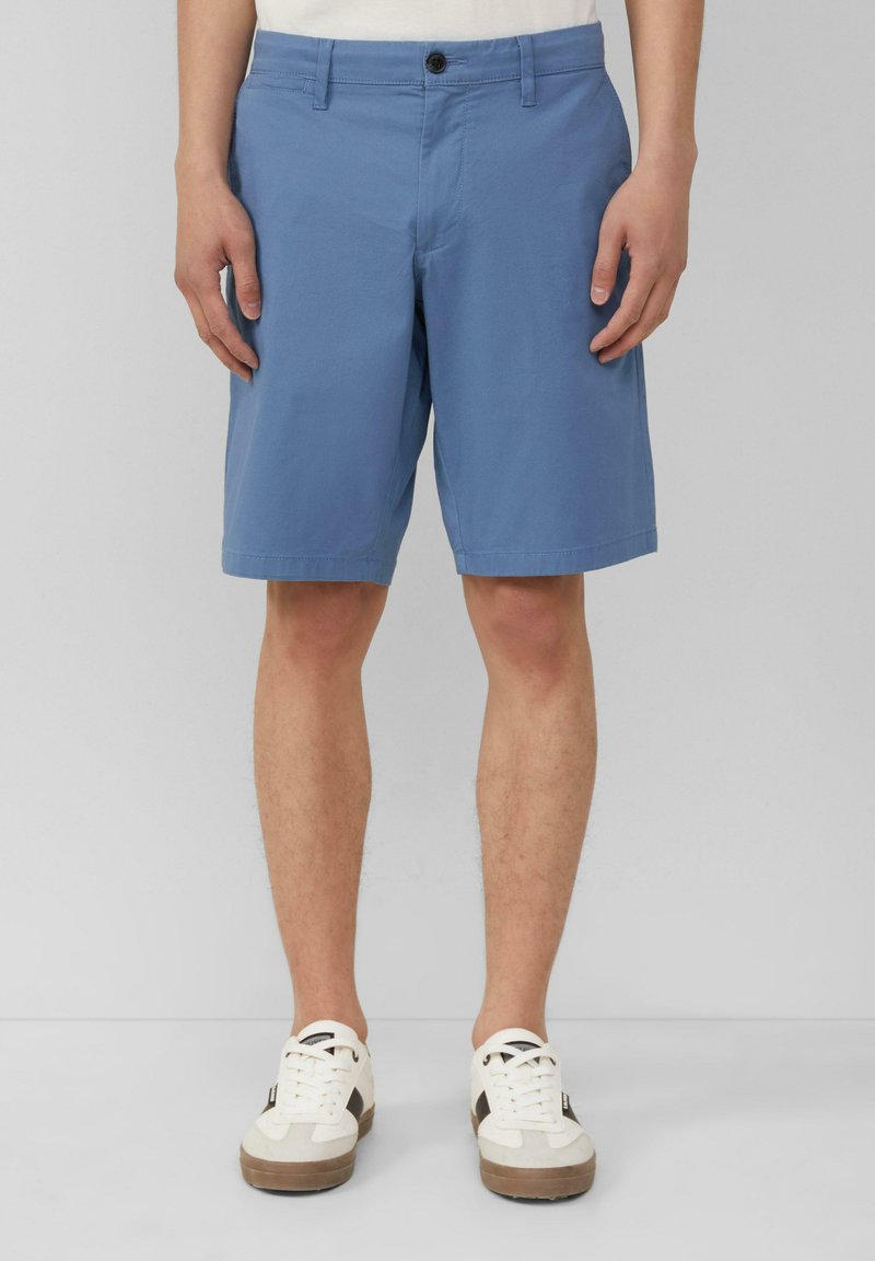 Lichtblauwe katoenen shorts met een vlakke voorkant, riemlussen en een enkele knoopsluiting. Gemaakt om te dragen met witte sneakers met zwarte accenten.