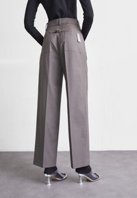 Grå skräddarsydda byxor med vida ben, med bakfickor och spänne på midjan. Kombineras med klara klacksandaler.