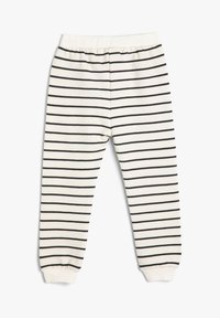 Joggers para niños pequeños de algodón con una base crema y rayas horizontales negras, cinturilla elástica y puños acanalados en los tobillos.