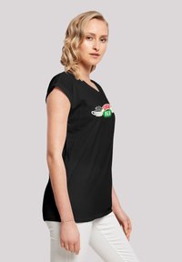 Schwarzes T-Shirt in lockerer Passform, mit einem bunten "Central Perk"-Grafik und einer Kaffeetasse auf der Vorderseite. Glatte Textur.