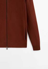 Bruine zip-up trui van textuur gebreide stof. Heeft geribbelde manchetten en zoom, met zijsplitten voor bewegingsgemak.