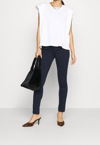 Vit kortärmad topp, mörka skinny jeans, leopardmönstrade mules och en svart faux fur-handväska. Enkelt mönster med rena linjer och texturer.