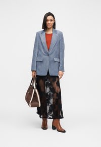 Lichtblauwe corduroy blazer, rood topje, zwarte kanten rok, bruine handtas met bontafwerking en bruine laarzen met blokhakken.