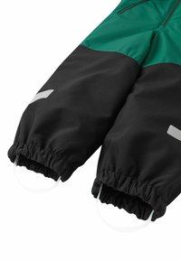 Groene en zwarte waterdichte, geïsoleerde sneeuwoverall. Kenmerken zijn elastische manchetten, heldere accenten en versterkte stiksels voor duurzaamheid.