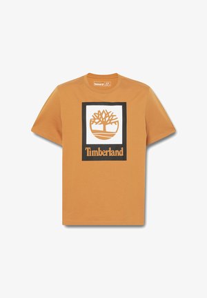 Short-sleeve orange cotton t-shirt featuring a central white square with a brown tree logo and "Timberland" text below in black.