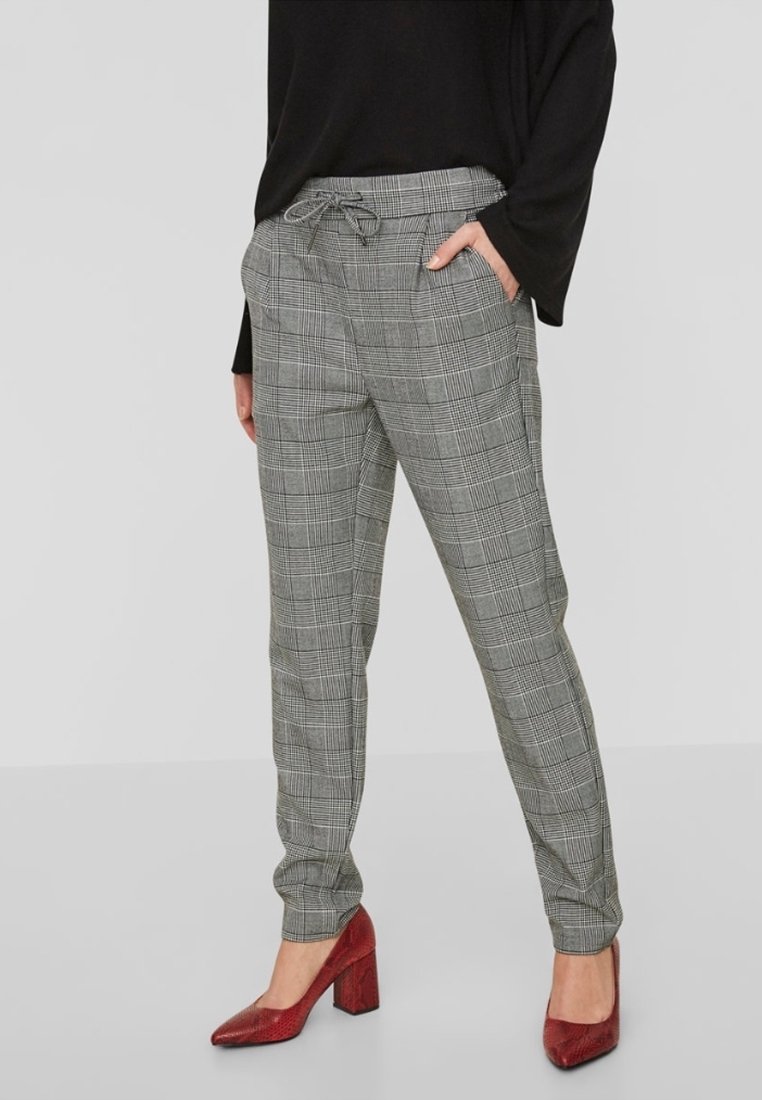 Grey plaid trousers with a drawstring waist, tapered leg, and visible side pockets. Worn with red block-heeled shoes.