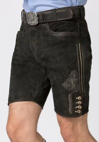 Pantaloni shorts in suede nero con ricami intricati, bottoni decorativi e una texture liscia. Progettati con una silhouette aderente e tasche laterali.