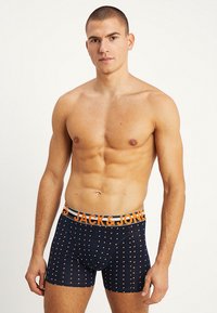 Boxer brevissimi da uomo in blu scuro con un motivo a pois arancioni. La vita elasticizzata presenta il logo "JACK & JONES" in arancione e grigio.