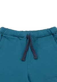 Türkisfarbene Jogginghosen aus weichem Stoff, mit einem elastischen Bund und einer dunkelblauen Kordel sowie Seitentaschen. Glatte Textur, lässiges Design.