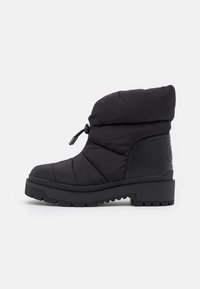 Bota negra acolchada con punta redondeada, parte superior acolchada, toggle ajustable y suela de goma texturizada para tracción. Diseño sencillo con detalles mínimos.