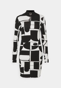 Robe moulante noire et blanche à manches longues avec des motifs géométriques abstraits et un col montant zippé à moitié avec un tire-zip circulaire.