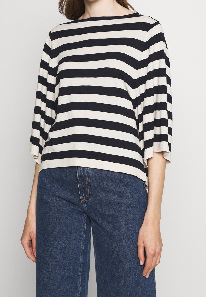Pasiasty top w kremowym i granatowym kolorze, z szerokim dekoltem boat i rękawami trzy czwarte. Miękki materiał z luźnym krojem.
