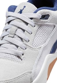 Vita sneakers som har en kombination av texturerad mocka och nättyger, med ljusblå accenter och vita skosnören. Snygg tan-färgad gummisula som är synlig.