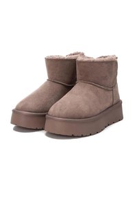 Botas de tobillo de ante marrón con forro de pelo sintético, suela de goma plana, diseño sencillo y detalles de costura alrededor del cuello.