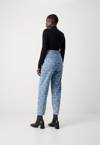 High-waisted blue jeans with a textured pattern and five pockets, paired with a fitted black long-sleeve top and black leather ankle boots.