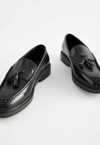 Sorte læder loafers med en blank finish, frynser, dekorativ syning og en lavprofil, tekstureret gummisål.
