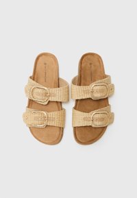 Svjetlosmeđi sandali s dva tkanja trake koja imaju zlatne kopče. Mekana faux suede podloga za stopala i ravna dizajn potplata za jednostavno nošenje.