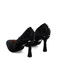 Zapatos de tacón alto negros con adornos con púas y acentos brillantes, que destacan por su superficie texturizada y un diseño de tacón esculpido.